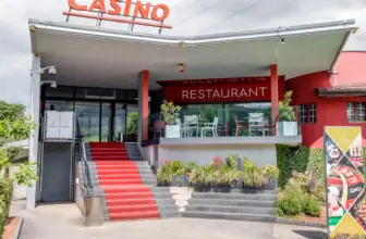 Eingang des Casino du Jura in Courrendlin mit roter Treppe und Restaurantterrasse