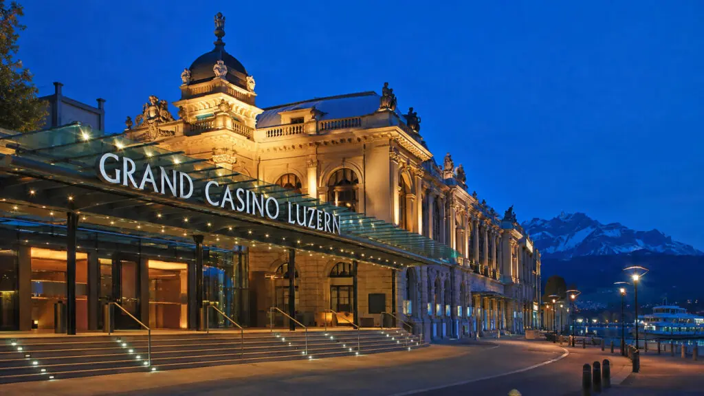 Grand Casino Luzern in der Abenddämmerung mit Bergpanorama und Seepromenade