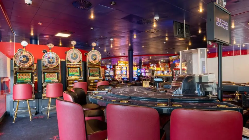 Spielautomaten und Roulettetisch mit roten Sesseln im Casino Barrière Fribourg