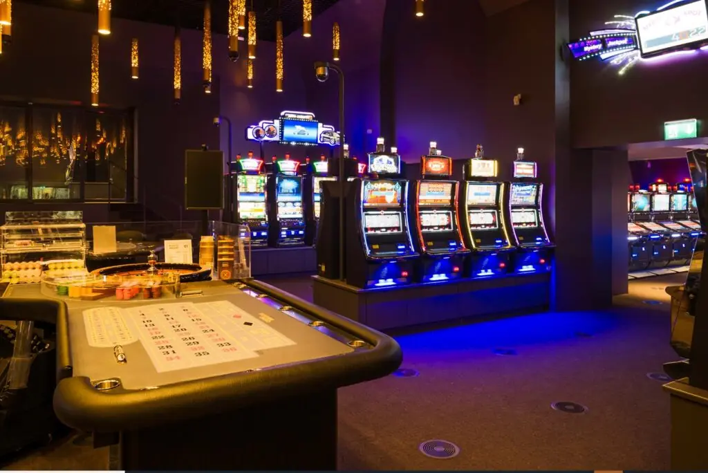 Spieltisch und Spielautomaten mit goldenen Lichterketten im Casino Neuchâtel