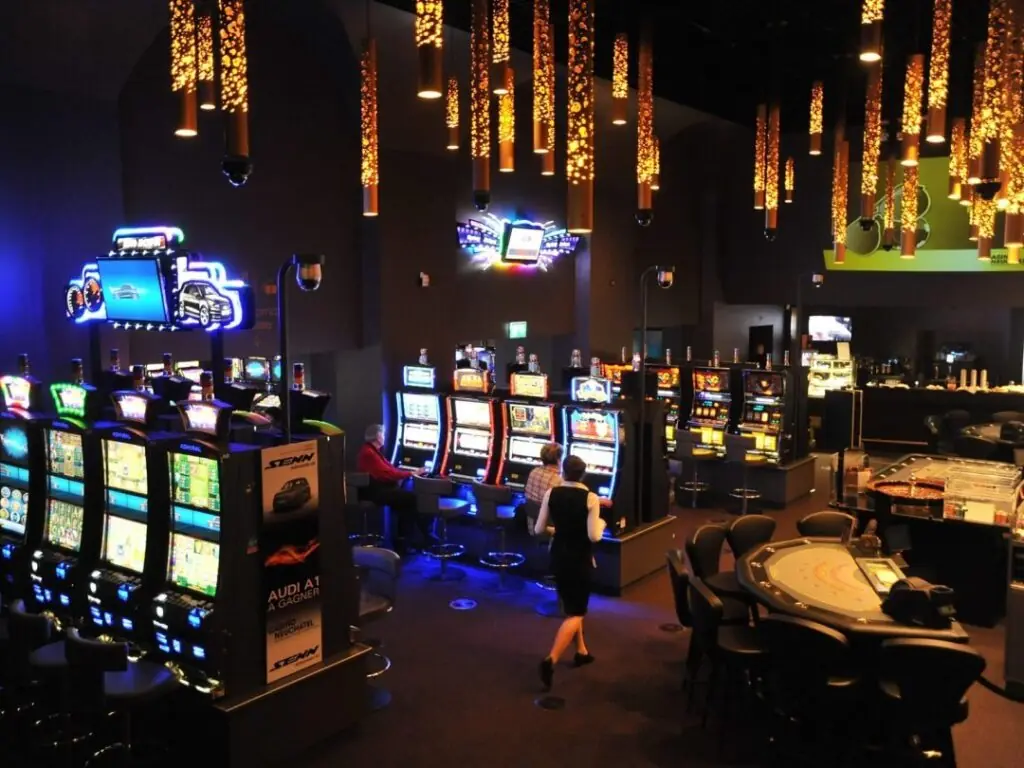 Spielautomaten und Spieltische unter Lichterketten im Casino Neuchâtel