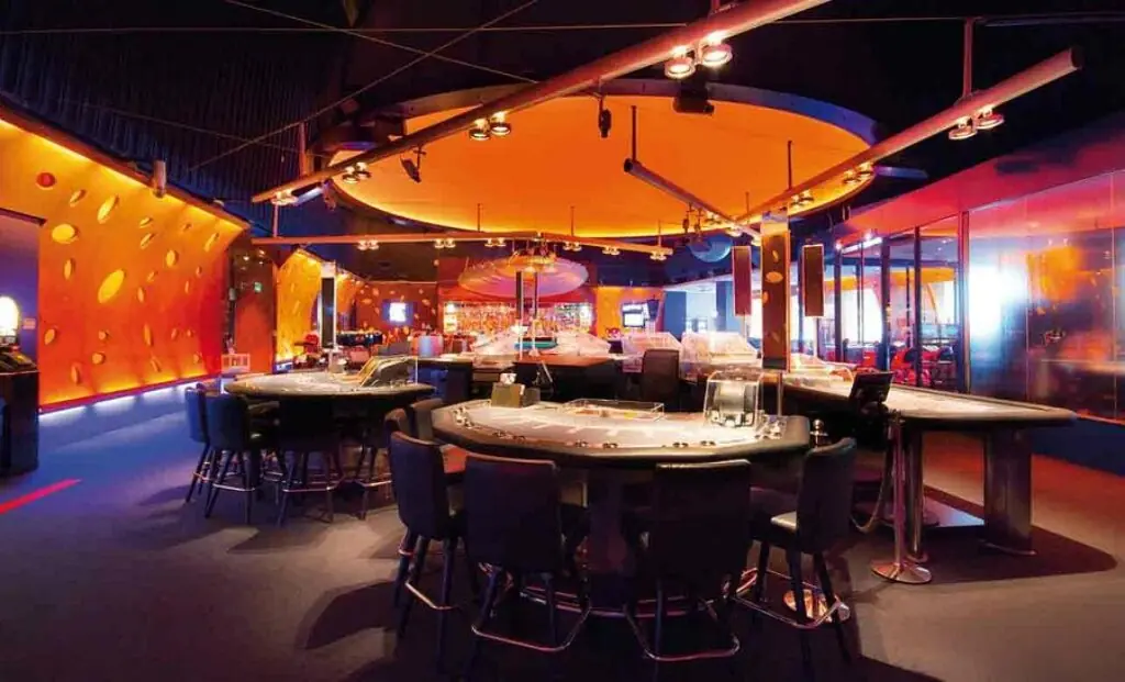 Spieltische unter orange beleuchteter Decke im Grand Casino Baden